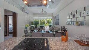 Eine moderne Küche mit Einbauherd, Deckenventilator und Essbereich mit Glastisch und Stühlen.