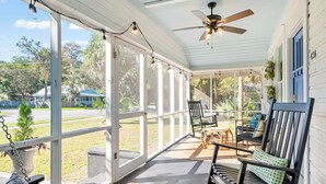 A covered porch with a ceiling fan, outdoor seating, and a view of the neighborhood. - Beautifully restored cottage downtown Historic Brunswick close to golf + beaches (Brunswick)