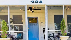 A building with a blue door, number 428, and a covered porch with chairs and planters. - Beautifully restored cottage downtown Historic Brunswick close to golf + beaches (Brunswick)