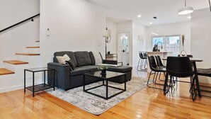 A modern living room with a sofa, coffee table, and dining area with chairs.