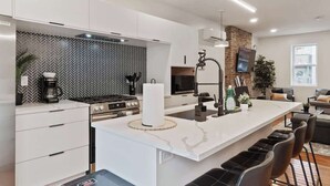 A modern kitchen with a large island, white cabinetry, and a herringbone tile backsplash.