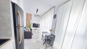 A modern kitchen with a black refrigerator, a dining area with a table and chairs, and a living room with a sofa and a TV. - THE PORT. E151A VacaHome Management (El Puerto de Santa María)