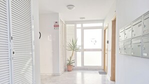 A hallway with a potted plant, a door with a window, and a row of metal lockers on the right. - THE PORT. E151A VacaHome Management (El Puerto de Santa María)