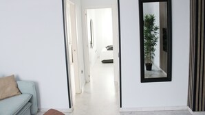Un couloir avec un canapé bleu clair, un miroir et une plante en pot.