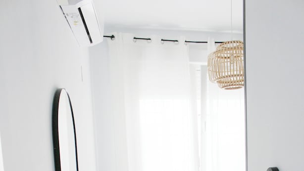 Une chambre à coucher moderne et minimaliste, avec un grand lit, un miroir et un luminaire en osier.