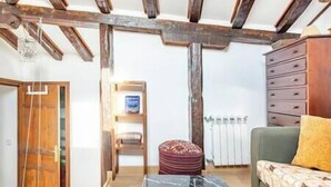 Une pièce avec des poutres apparentes, une porte en bois, un radiateur, un canapé et une petite table.