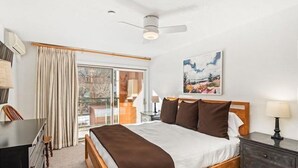 A hotel room with a bed, a desk, a chair, a dresser, a ceiling fan, and a window with curtains. - Gold-rated 2 Bedroom Condo at the Base of Aspen Mountain (Aspen)