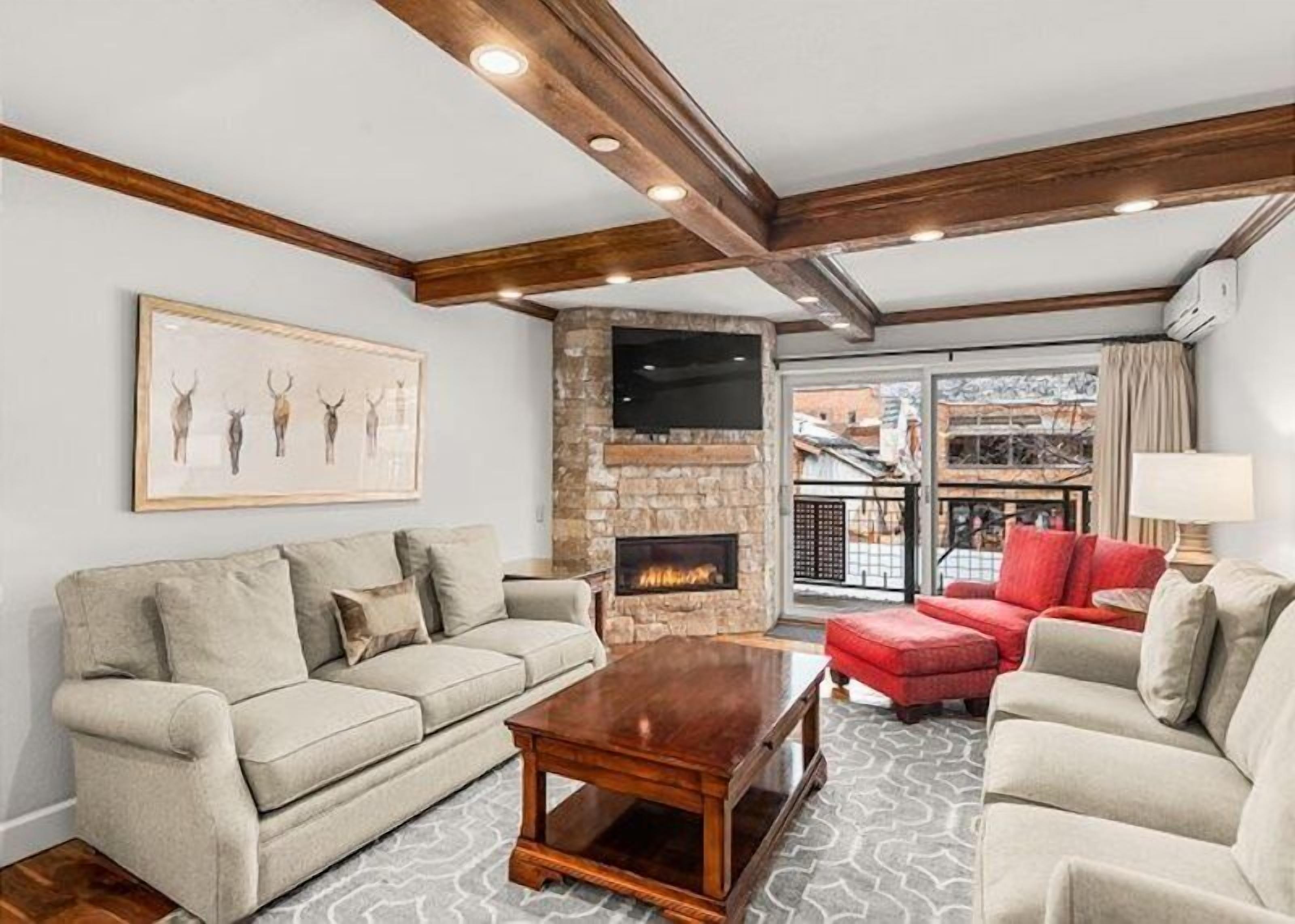 A living room with a stone fireplace, a sofa, a red armchair, and a coffee table.