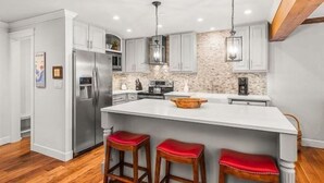 A modern kitchen with a large island, stainless steel appliances, and wooden stools. - 2 Bedroom Premier Vacation Rental in Downtown Aspen - Steps From Gondola! (Aspen)