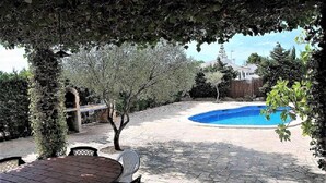 Ein Garten mit Schwimmbad, Stein-Terrasse und Sitzgelegenheit im Freien.