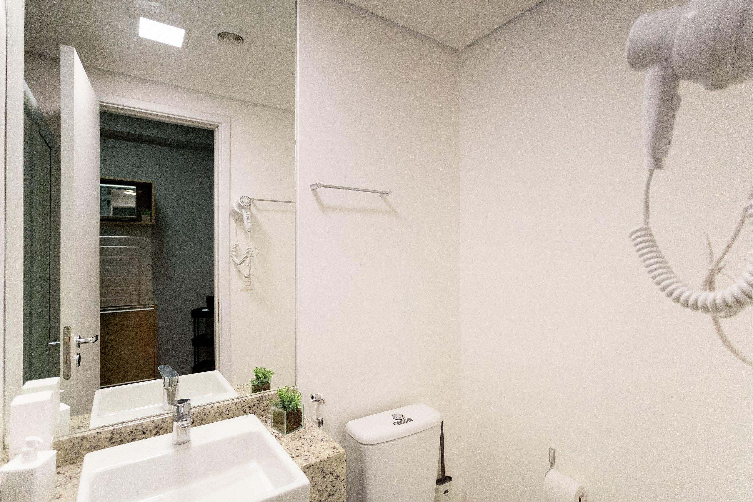 A bathroom with a sink, mirror, towel rack, and a hairdryer.