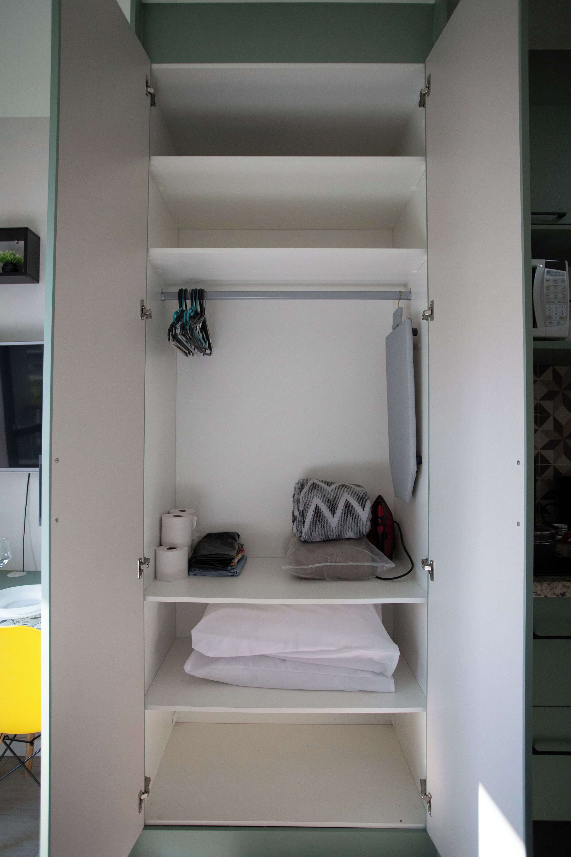 A wardrobe with multiple shelves, a hanging rack, and a mirror.