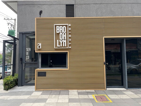 A modern building facade with a prominent sign reading "BRO OH LYN" and a small window with a sign "SETIN". - Brooklyn Studios (São Paulo)