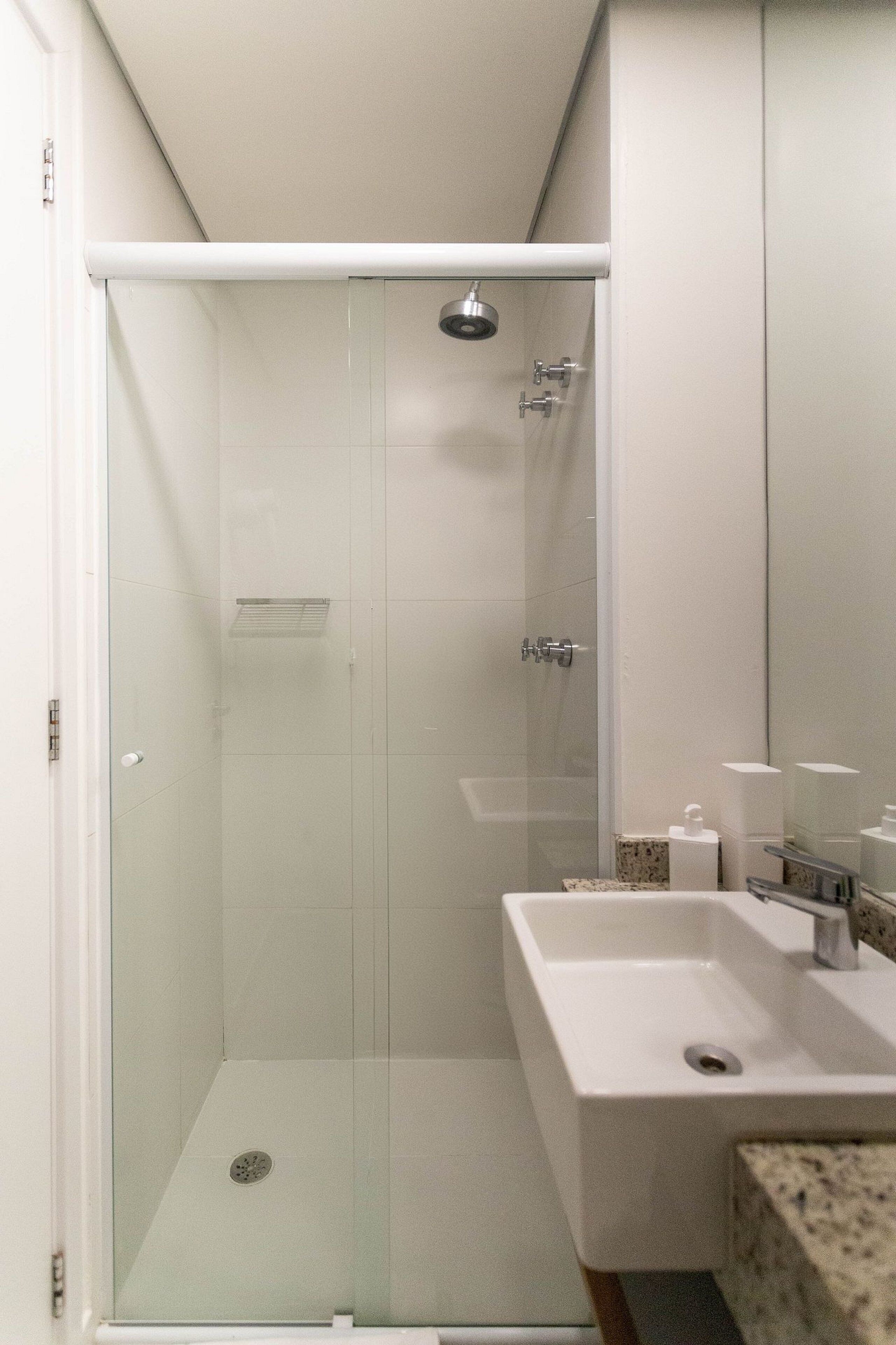 A modern bathroom with a glass-enclosed shower, a white sink, and a marble countertop.