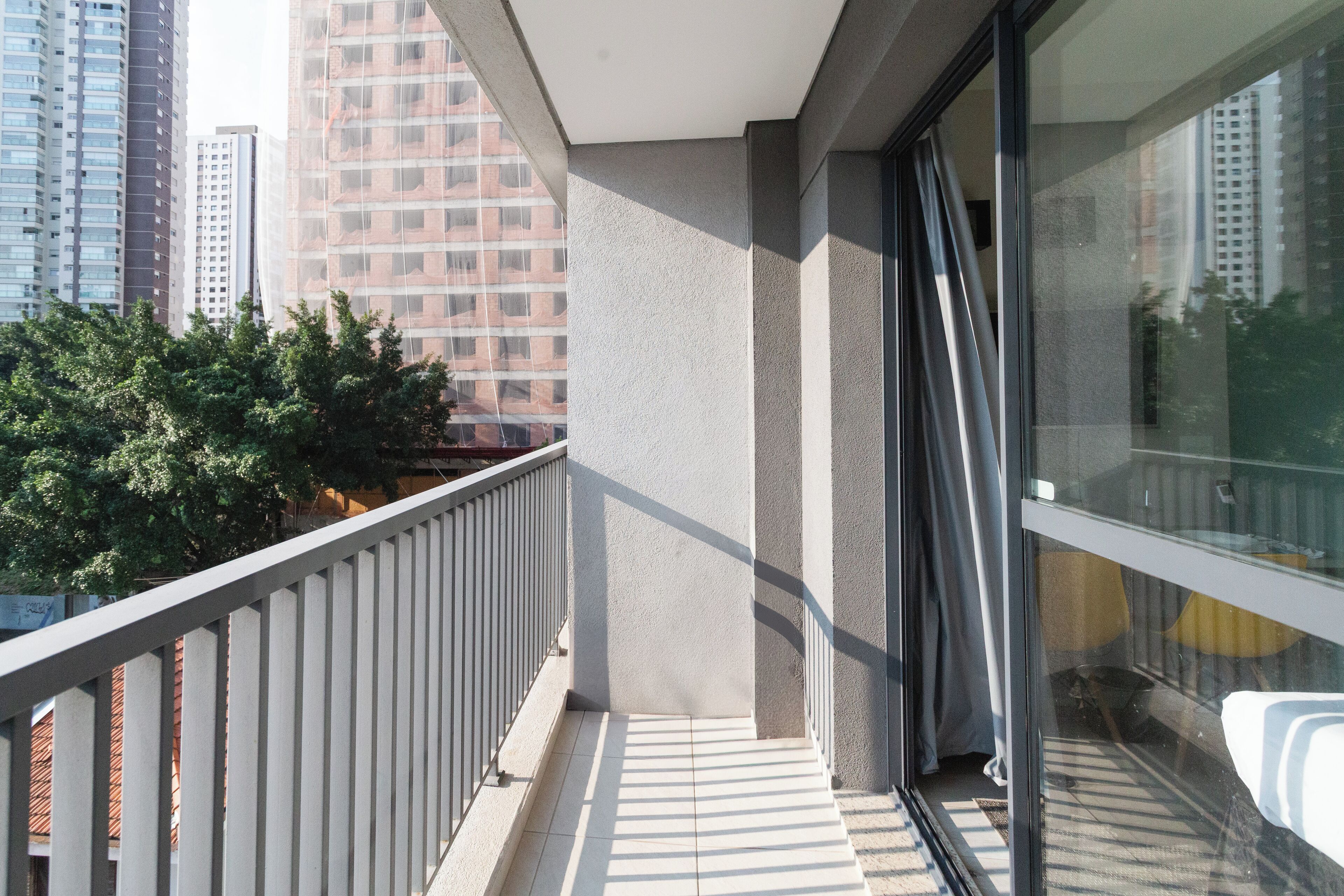 A balcony with a view of tall buildings and trees.