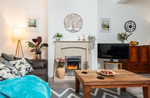 A living room with a fireplace, a television, and a sofa. - Stylish Home Retreat on Outskirts of Liverpool (St Helens)