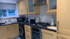 Une cuisine moderne avec des meubles de couleur beige, un lave-linge encastré, une cuisinière et un four à micro-ondes.