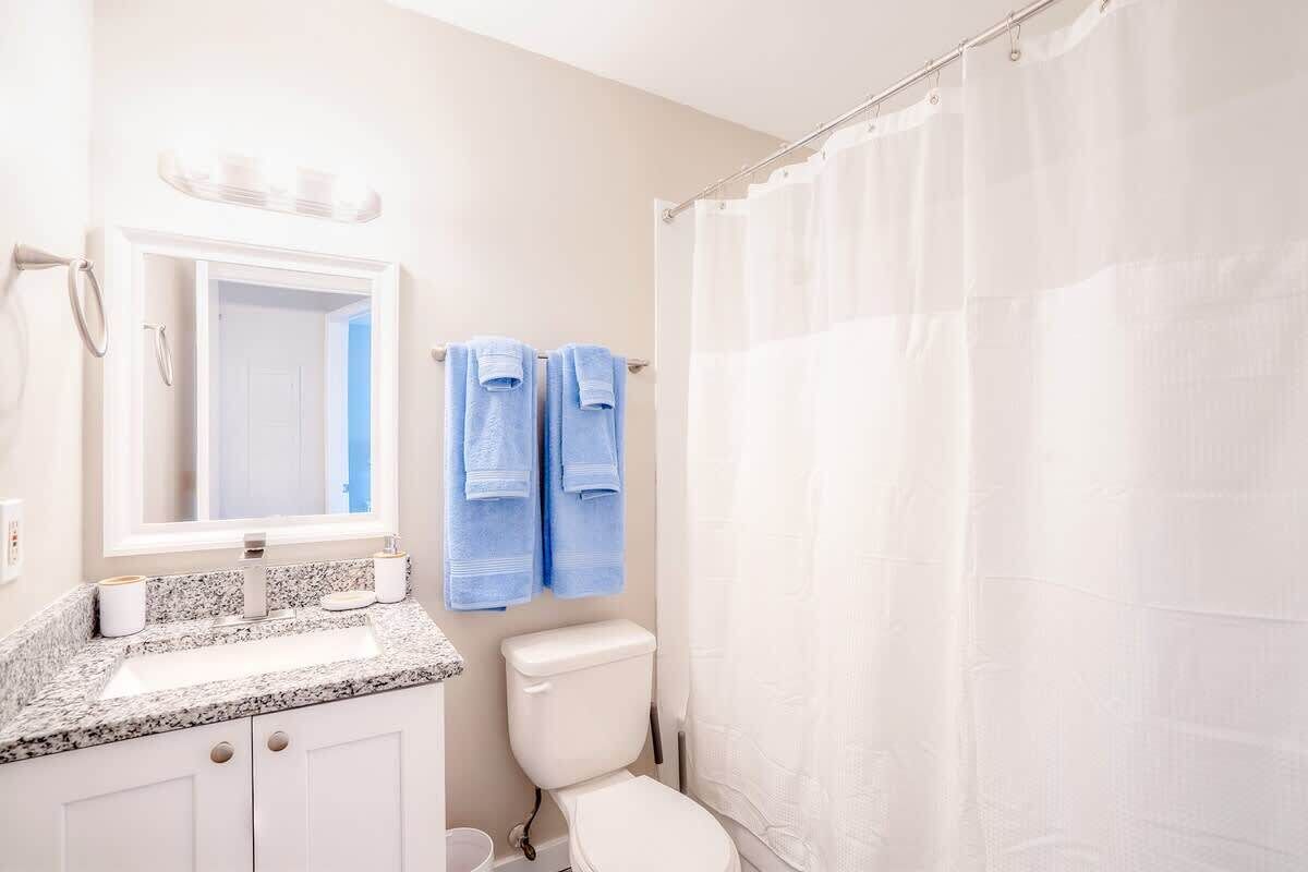 Un baño con lavamanos blanco, inodoro y cortina de ducha.