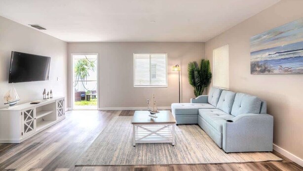 A living room with a TV, a sofa, a coffee table, and a painting on the wall.