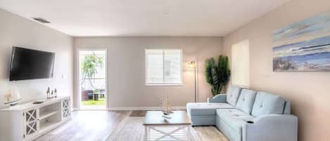 A living room with a TV, a sofa, a coffee table, and a painting on the wall.