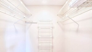 A white interior with a central metal shelving unit, white walls, and a wooden floor.