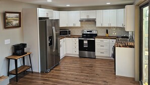 A modern kitchen with white cabinets, stainless steel appliances, and a wooden floor. - SMITH LAKE CABIN-Cave, Dock,  (Crane Hill)