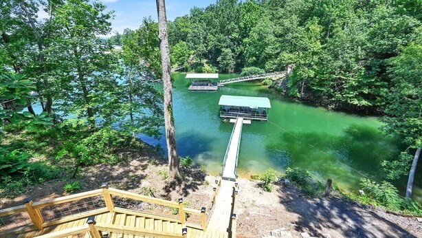A wooden deck leading to a river with a bridge and a dock. - SMITH LAKE CABIN-Cave, Dock,  (Crane Hill)