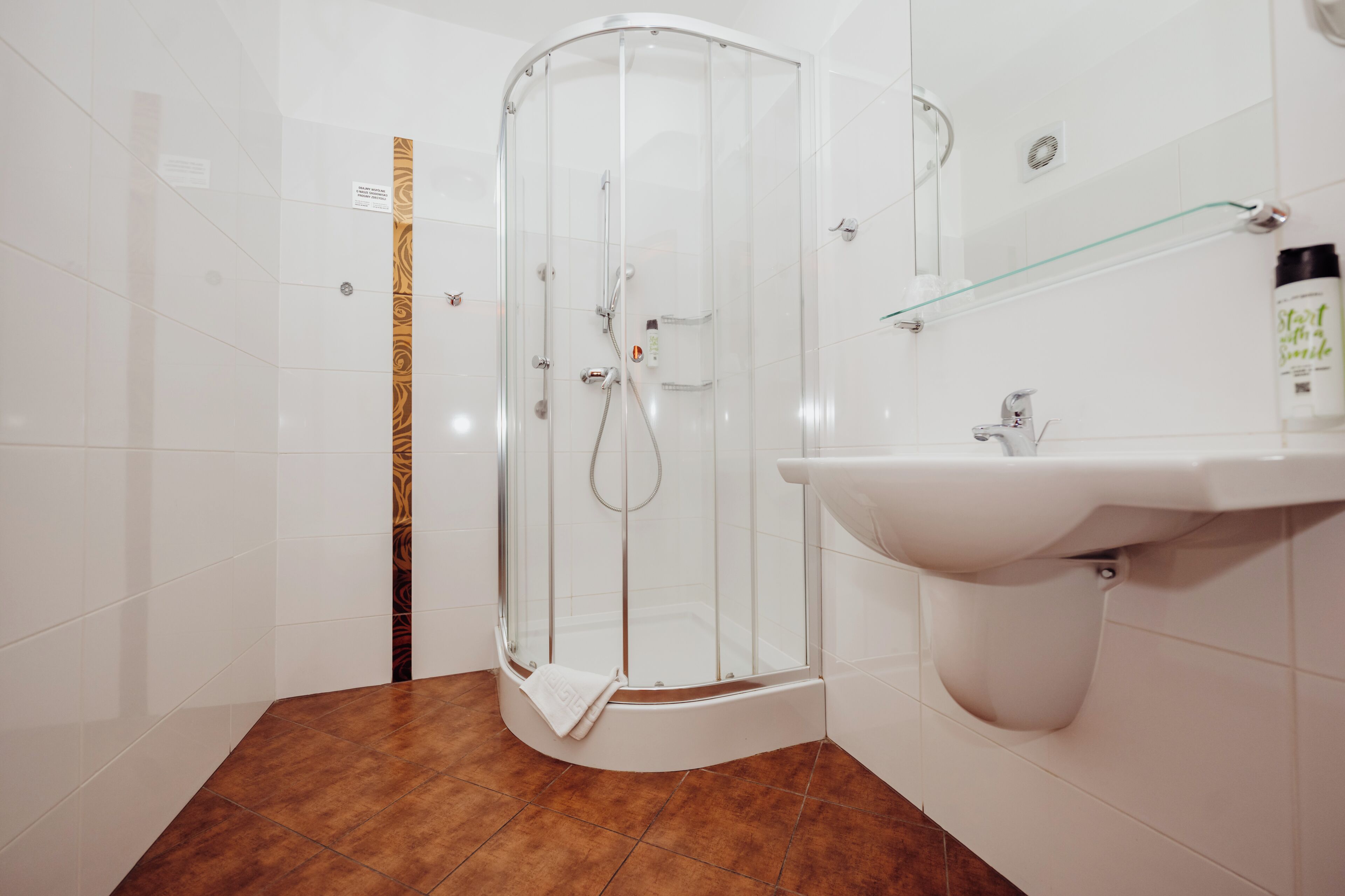 A modern bathroom with a glass-enclosed shower, a white sink, and a tiled floor.