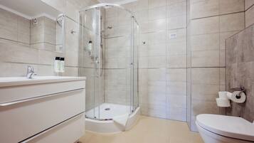 Un baño con ducha de mampara de vidrio, inodoro y tocador con espejo.