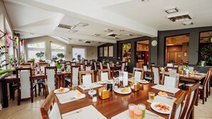 A spacious dining area with multiple tables and chairs, large windows, and a variety of plants. - Instytut Zdrowia Sofra Fit & SPA Karpacz (Karpacz)