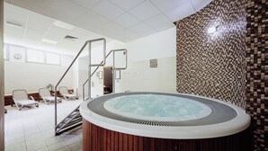 A spa area with a hot tub, lounge chairs, and a tiled wall. - Instytut Zdrowia Sofra Fit & SPA Karpacz (Karpacz)