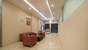 Amplia sala de estar con piso de mármol, dos sofás, una mesa de centro y ventiladores de techo.