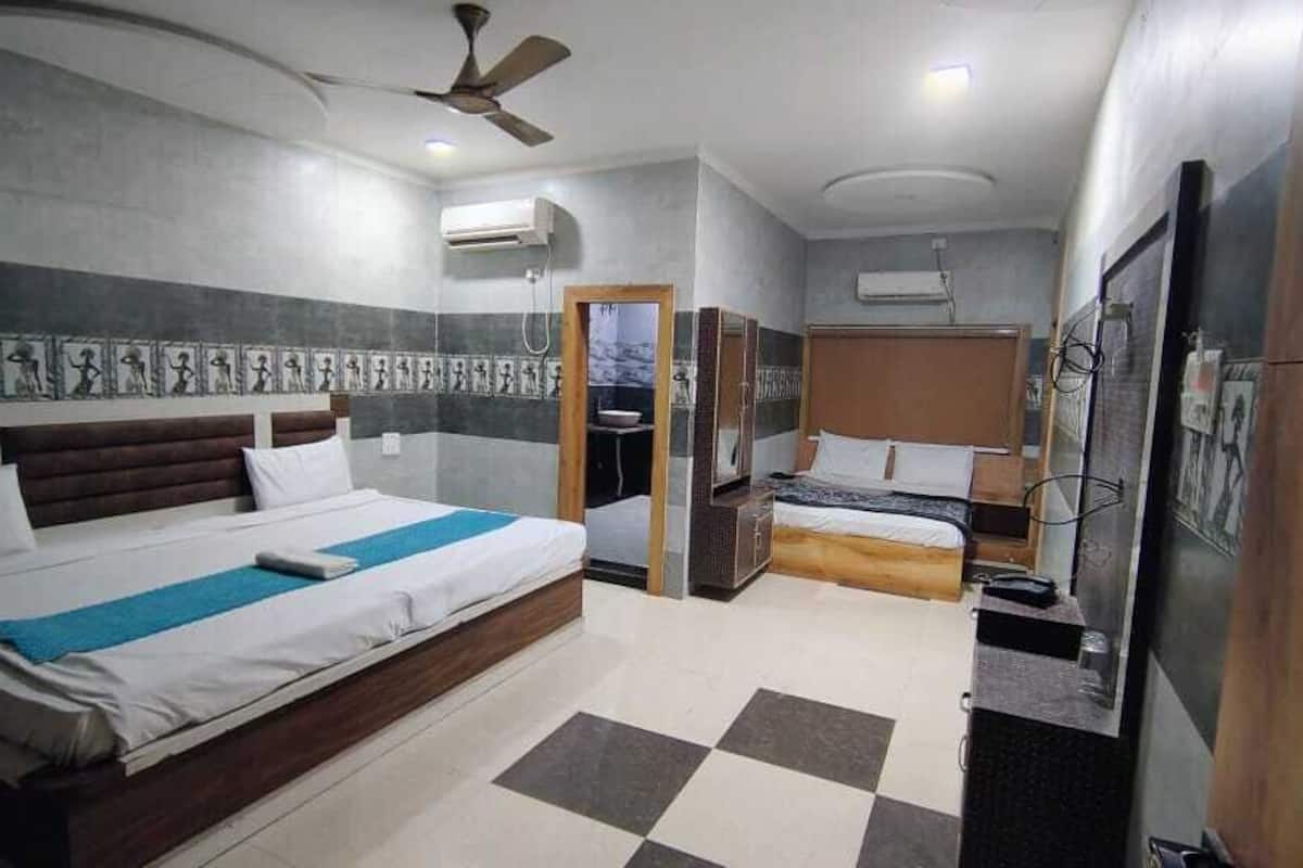A hotel room with a large bed, a smaller bed, a desk, and a wardrobe.