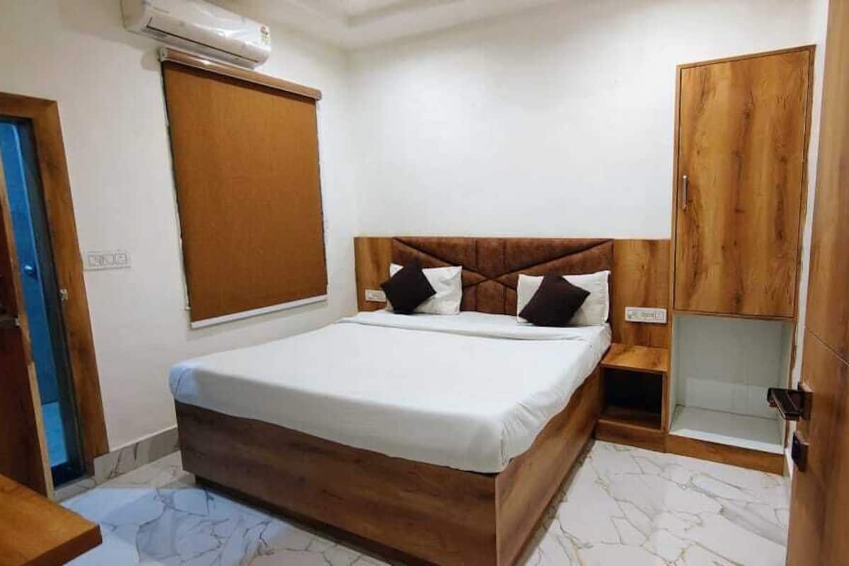A bedroom with a bed, wooden headboard, a wardrobe, and a window with a blind.
