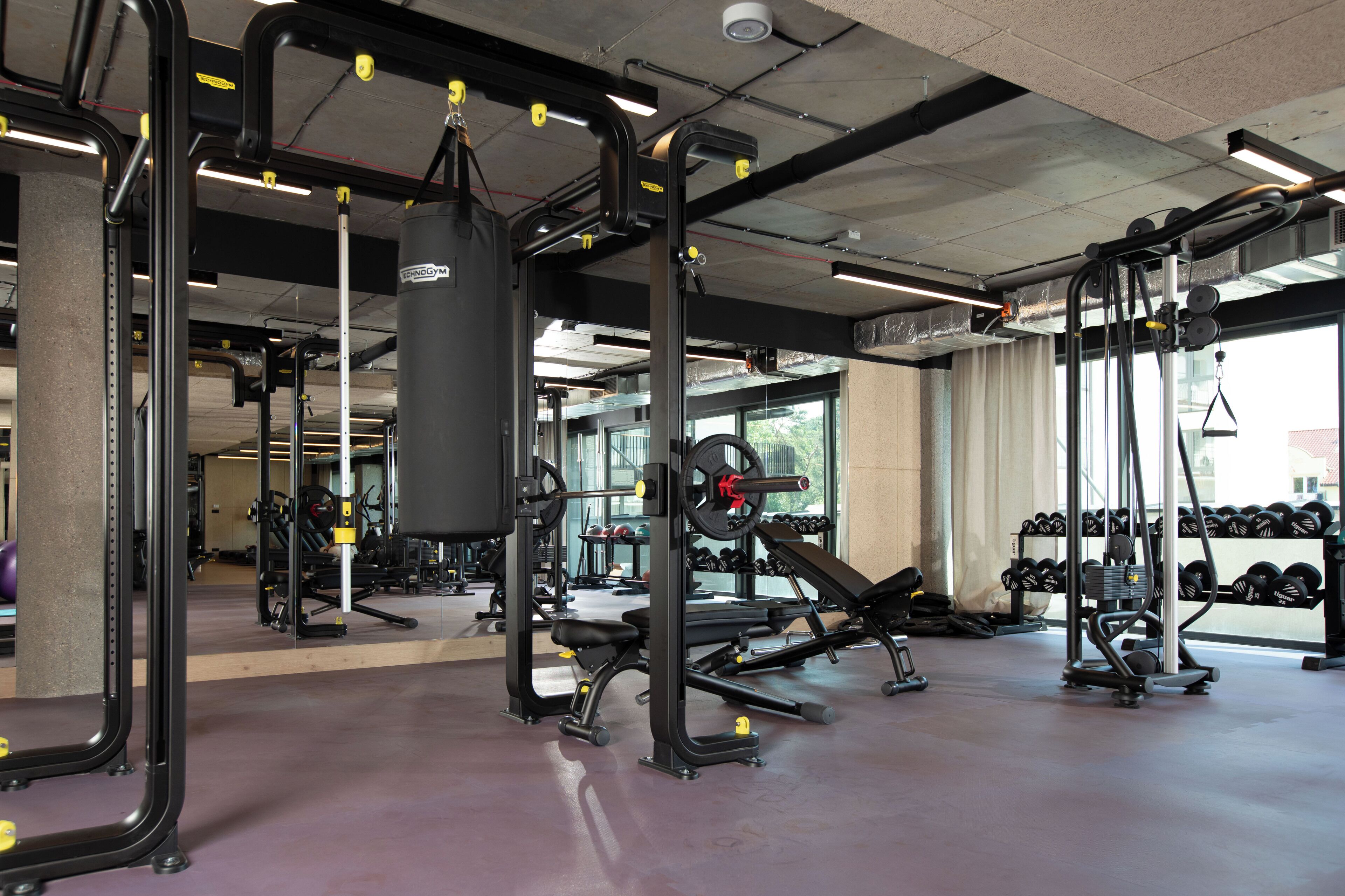A gym with weightlifting equipment, benches, and dumbbells.