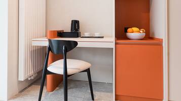 A modern room with a desk, chair, and a fruit bowl on a shelf.
