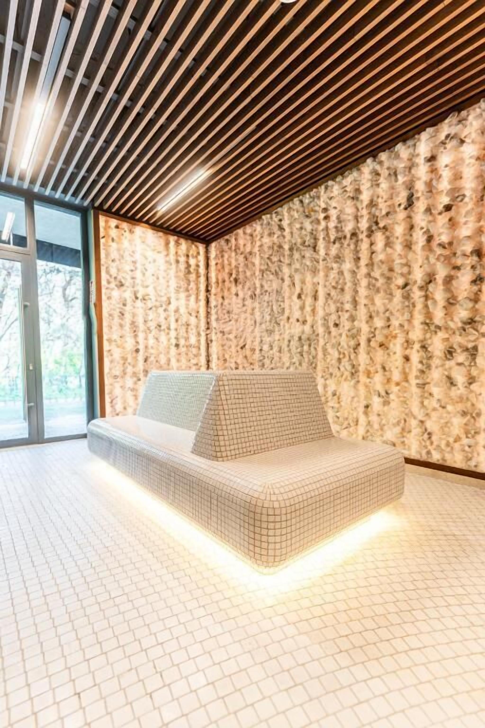 A modern room with a geometric-patterned sofa, a wooden slatted ceiling, and a textured wall.