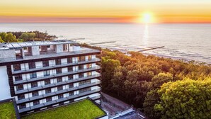 Ein modernes Gebäude mit mehreren Balkonen, das auf ein Gewässer im Abendrot blickt.