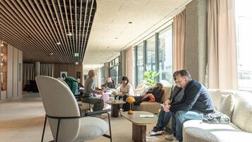 A spacious lobby with modern furniture, large windows, and a unique ceiling design.