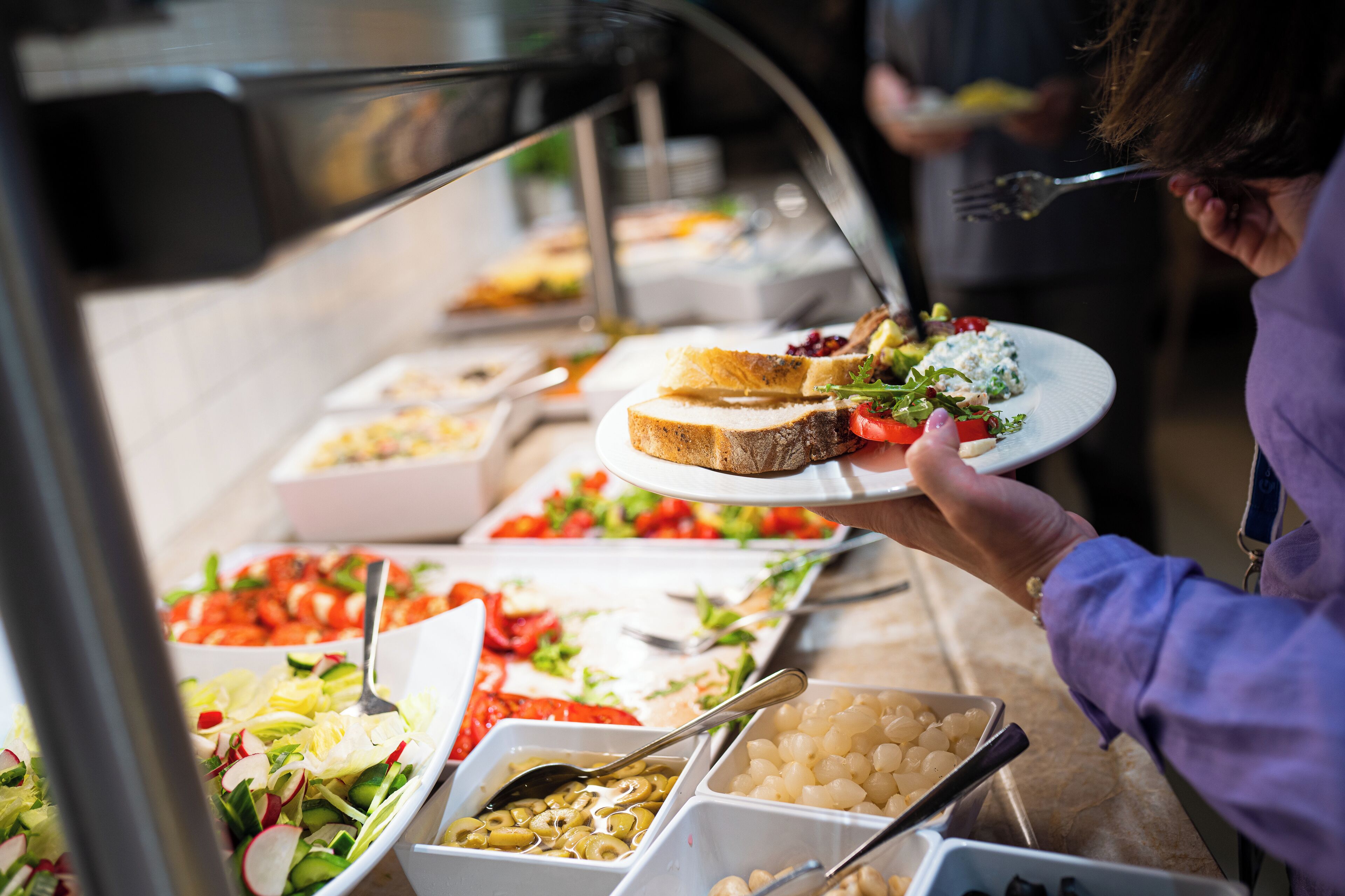 Un bufé con diversas opciones de comida, como ensaladas, frutas y pan.