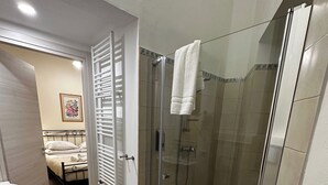 A modern bathroom with a glass-enclosed shower, a toilet, and a bed visible through an open door. - Double Room with private bathroom in Terralba (Oristano) - Lentisco (Terralba)