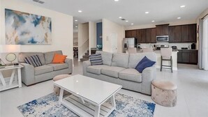 Una sala de estar moderna con dos sofás grises, una mesa de centro blanca y una alfombra estampada en azul y blanco.