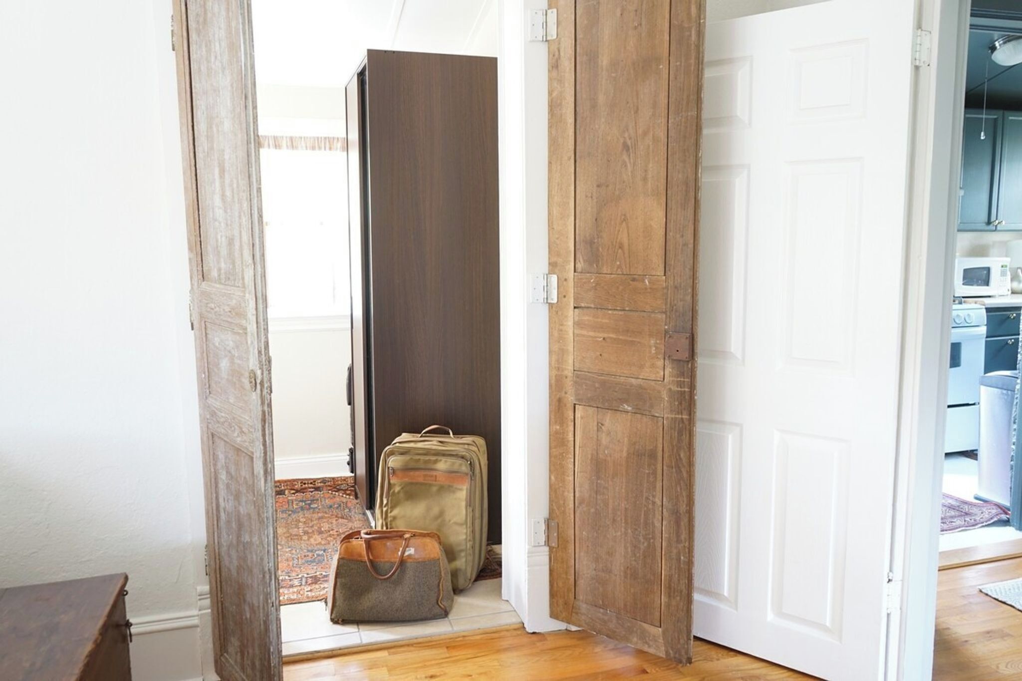 A hallway with a wooden door, a rug, and two bags.