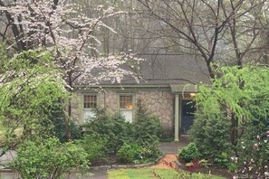 A stone house with a green door, surrounded by lush greenery and flowering trees. - DesignerCottage-Heart of 5 Points 2BR1Bath+Kitchen (Athens)