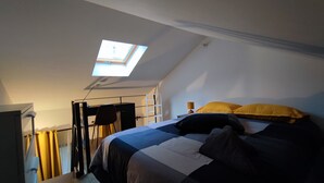 A bedroom with a skylight, a bed with pillows, a desk, and a chair. - Jardin Secret Greenhouse (Ivry-sur-Seine)