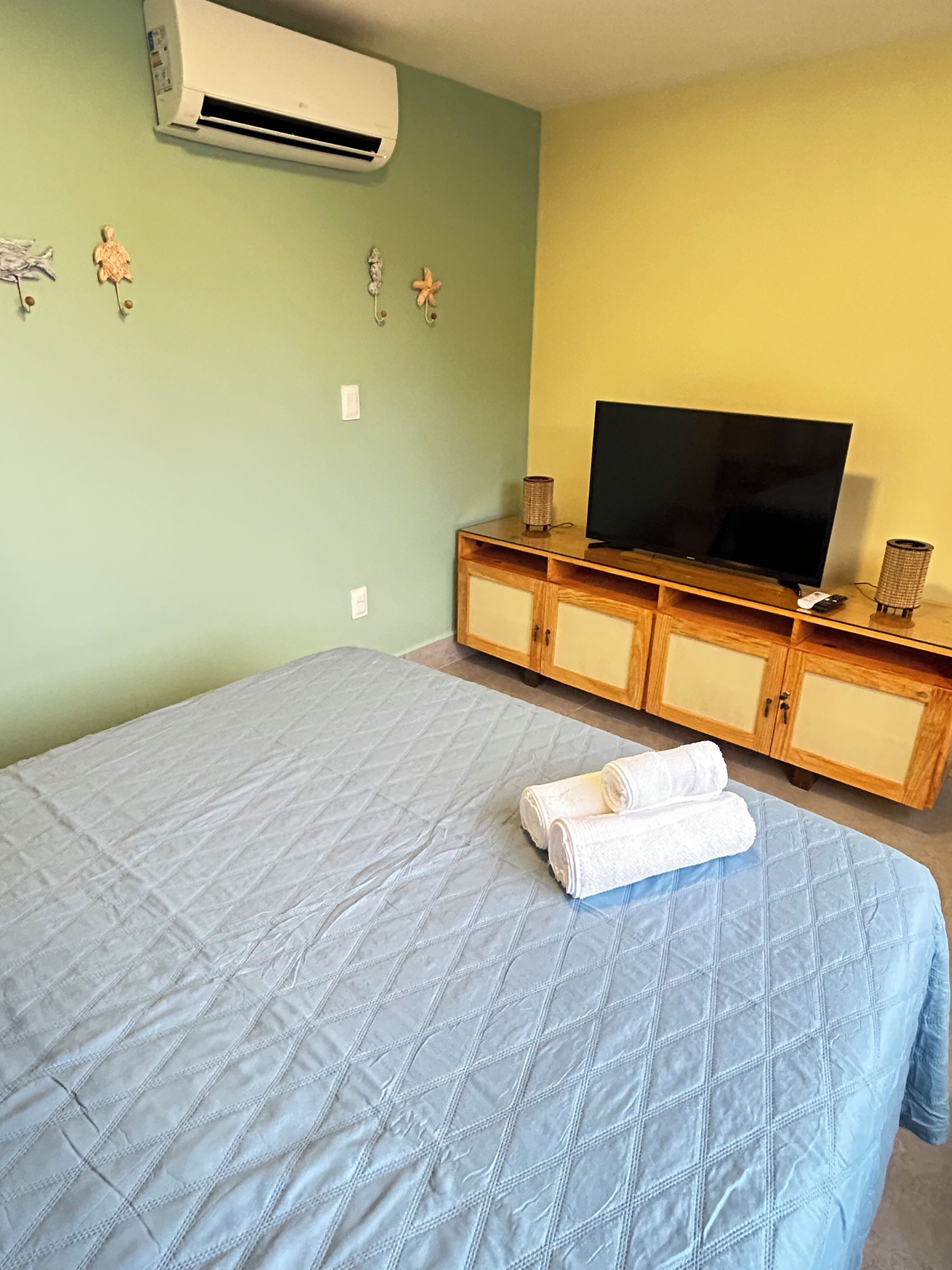 A bedroom with a bed, a TV, and a wooden cabinet.
