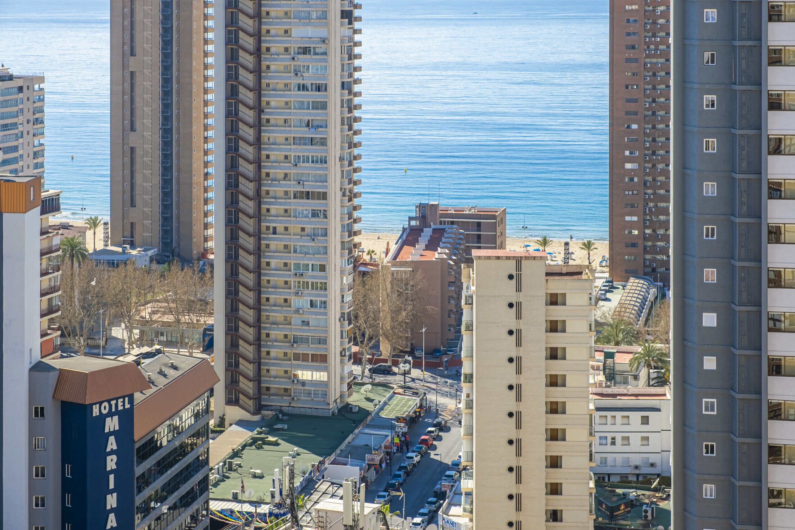 Un hotel de gran altura con varios pisos, una piscina en la azotea y vistas al mar.
