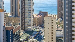 A high-rise hotel with multiple floors, a rooftop pool, and a view of the sea.