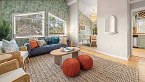 Een woonkamer met een blauwe bank, een ronde salontafel, en een eethoek met een tafel en stoelen.