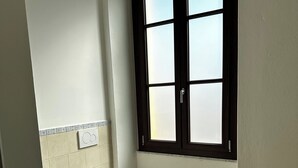 A bathroom with two toilets, a window with frosted glass panes, a tiled backsplash, and a wooden floor. - Double Room with private bathroom in Terralba (Oristano) - Juniper (Terralba)